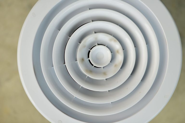 Rond wit afzuigventiel met concentrische ringen en wat stofaanslag, van dichtbij
