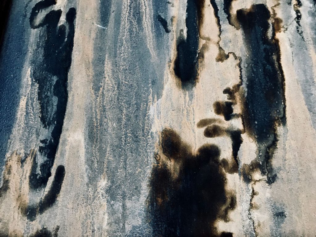 Dark black mildew stains spreading over a weathered wall surface