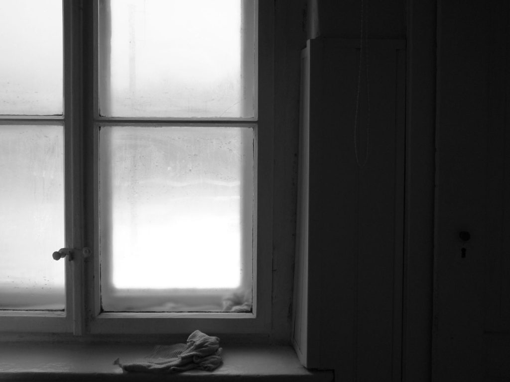 Fogged-up window panes on a cold day with a cloth left on the windowsill to wipe up the water