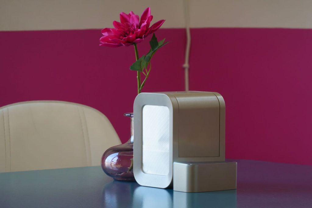 Compact portable air purifier on a table next to a glass vase with a pink flower