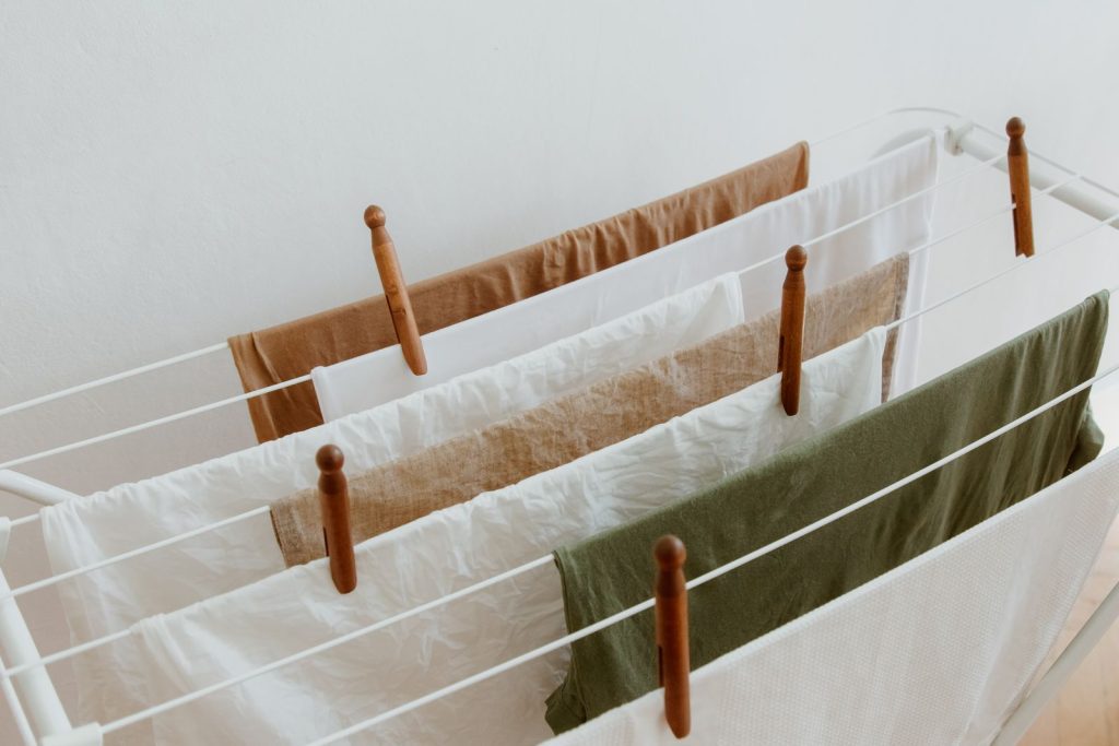 Clothes pegged with wooden clothespins on a white indoor drying rack
