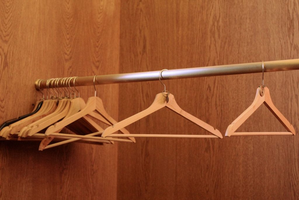 Empty wooden hangers on a metal rail inside a wood-paneled closet
